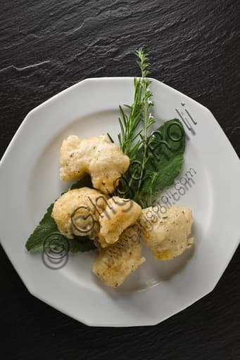 Piatto di baccalà fritto croccante aromatizzato con foglie di salvia e rametti di rosmarino fresco