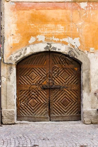 Porta in legno antico di un'abitazione storica a Bormio, dettaglio dei ferri battuti e del massello.